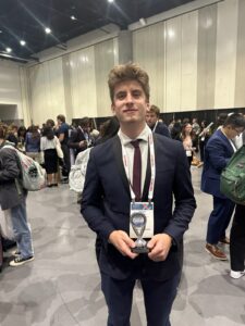 Male student holding award at a conference