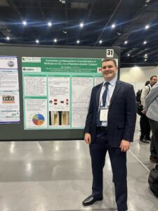 Male student stands in front of academic research poster