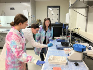 Professor in lab with two female students